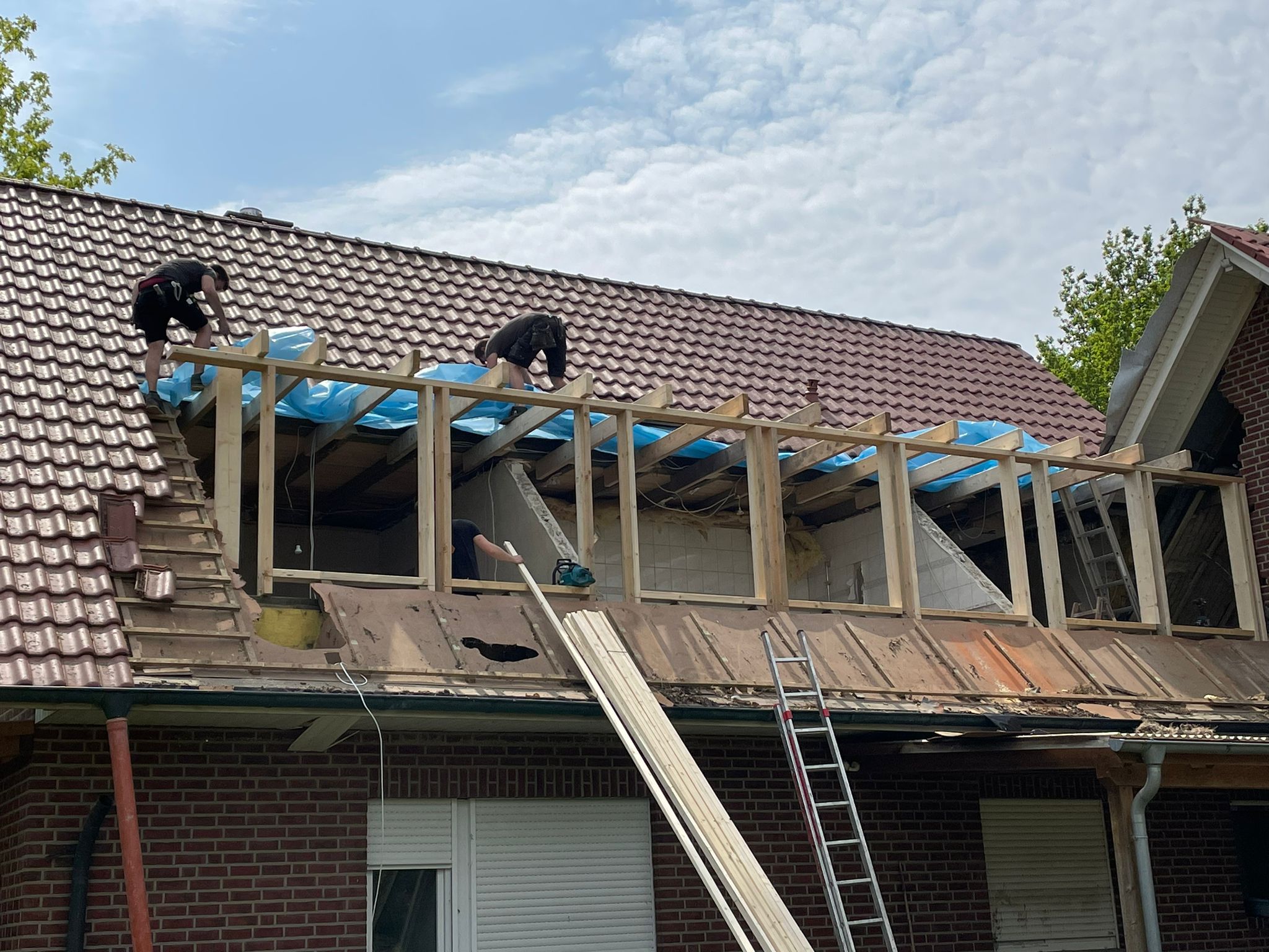 Ein offenes Dach, an dem mit einem Holzrahmen neue Fenster verbaut werden.